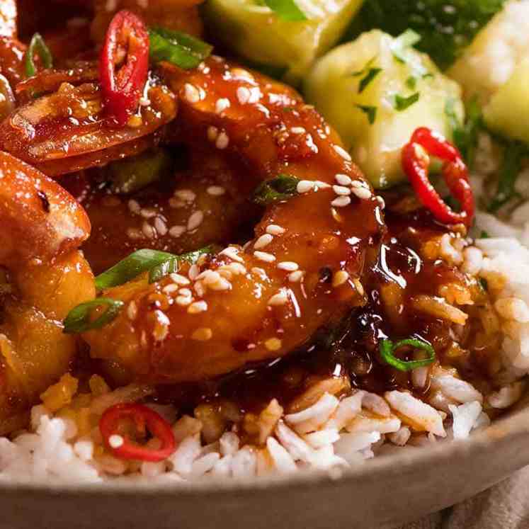 Close up of Asian Chilli Garlic Prawns served over rice with a quick Asian cucumber side salad