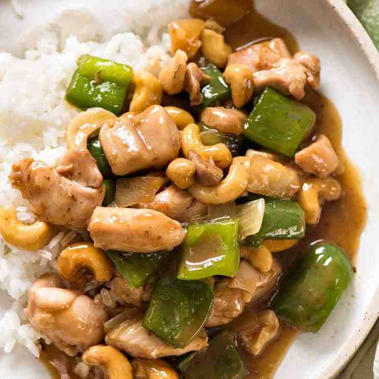 Chinese Cashew Chicken served on rice in a white bowl with chopsticks, ready to be eaten