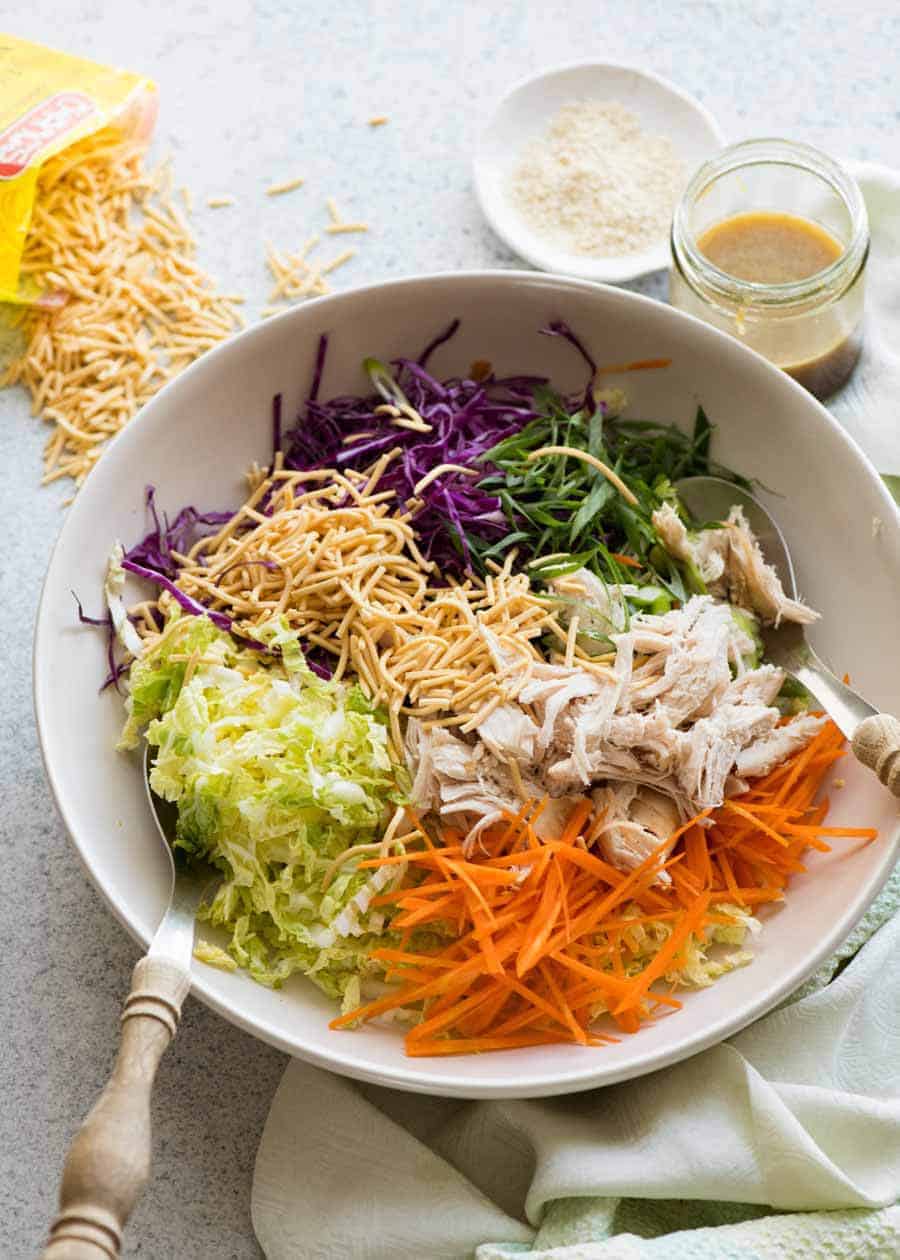 Chinese Chicken Salad with Asian Dressing in a white bowl, ready to be tossed