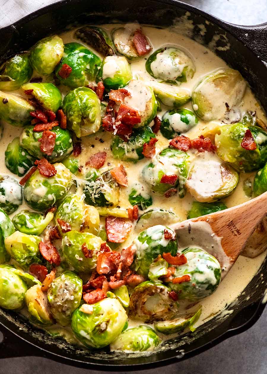Brussels Sprouts in a creamy sauce with bacon in a skillet, fresh off the stove