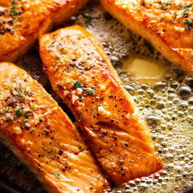 Garlic Butter Salmon in a skillet surrounded by foaming garlic butter