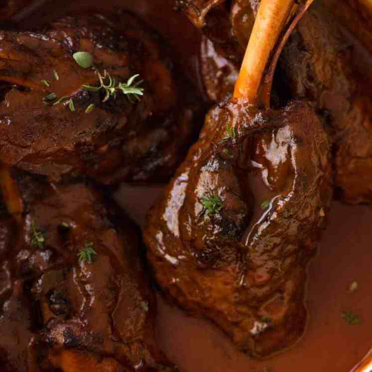 Slow Cooked Lamb Shanks in Red Wine Sauce in a cast iron pot, fresh off the stove ready to be served
