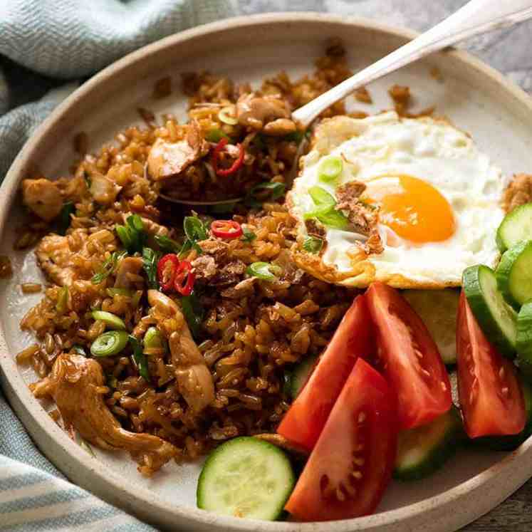 Nasi Goreng on a plate with a side of fried egg, tomato and cucumbers