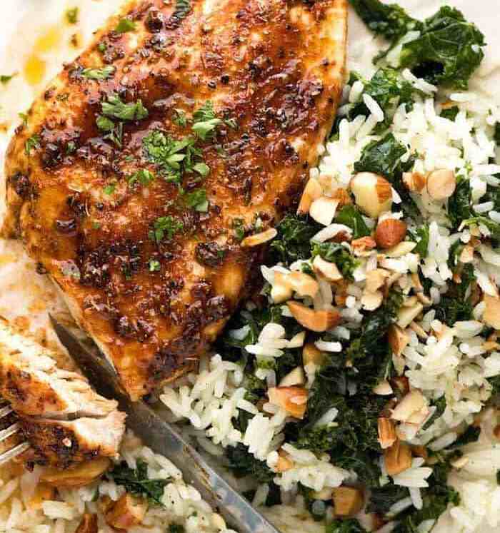 Baked Chicken Breast with a side of Garlic Butter Rice with Kale on a white plate, ready to be eaten.