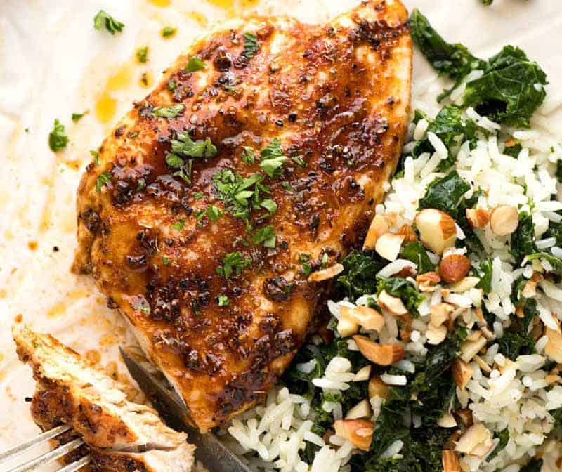 Juicy Oven Baked Chicken Breast on a white plate with a side of Garlic Butter Kale Rice