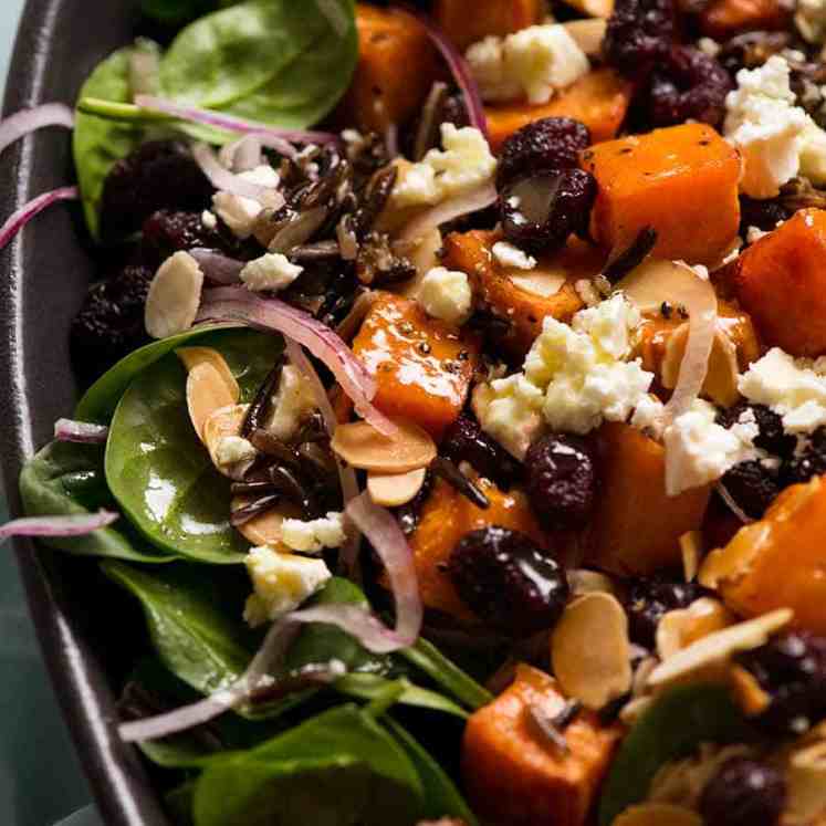 Close up of sweet potato salad with baby spinach, feta, almonds, red onion, wild rice drizzled with a Honey Lemon Dressing