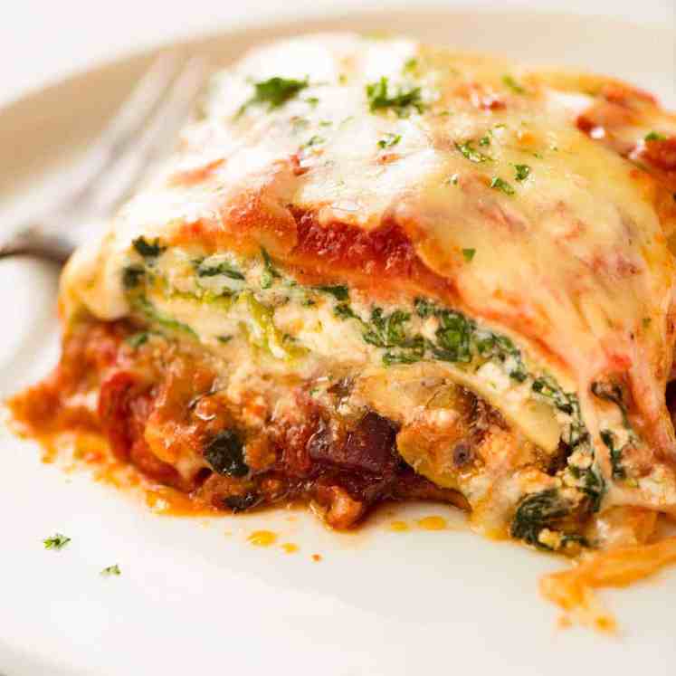 Close up of a slice of Vegetable Lasagna on a white plate, ready to be eaten