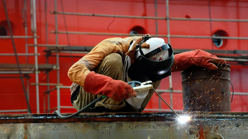 An Indonesian shipyard worker in Batam doing a welding work