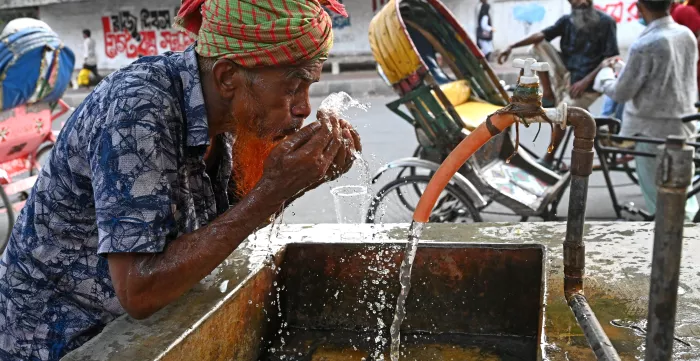 A rickshaw driver washing his face with water at a roadside water pipeline during heatwave weather in Dhaka, Bangladesh, on April 27, 2024