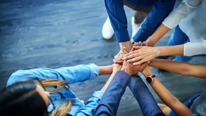 Group with hands together symbolizing collaboration, teamwork, partnership and goals