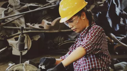 Female mechanic wearing hard hat at work.