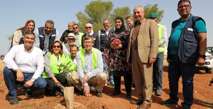 group of people around newly planted tree