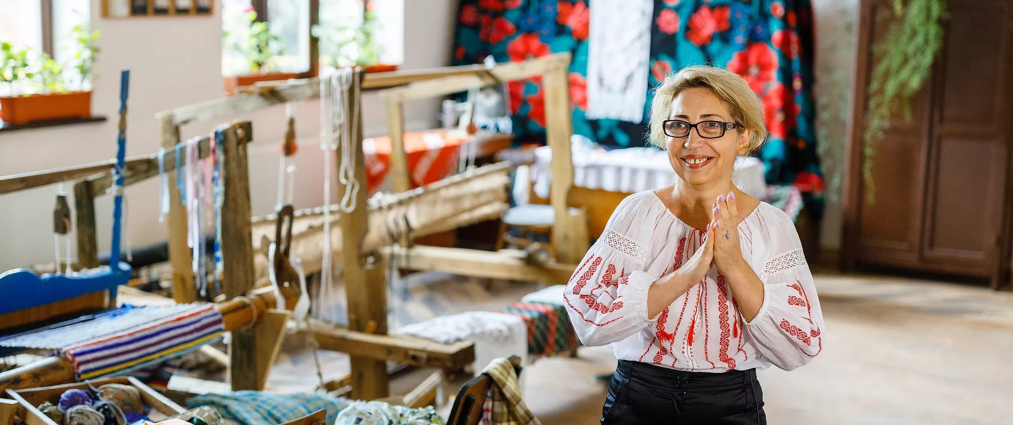 A women standing by a sewing machine in her embroidery workshop.