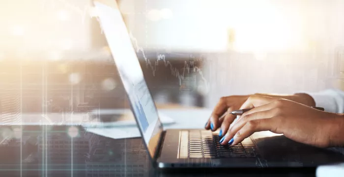 The hands of a woman typing on a laptop with virtual overlay with a financial strategy