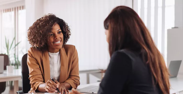 A woman sitting at a table talking to another woman 