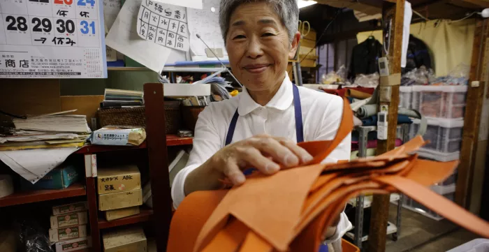 Japanese woman holding a stack of papers.